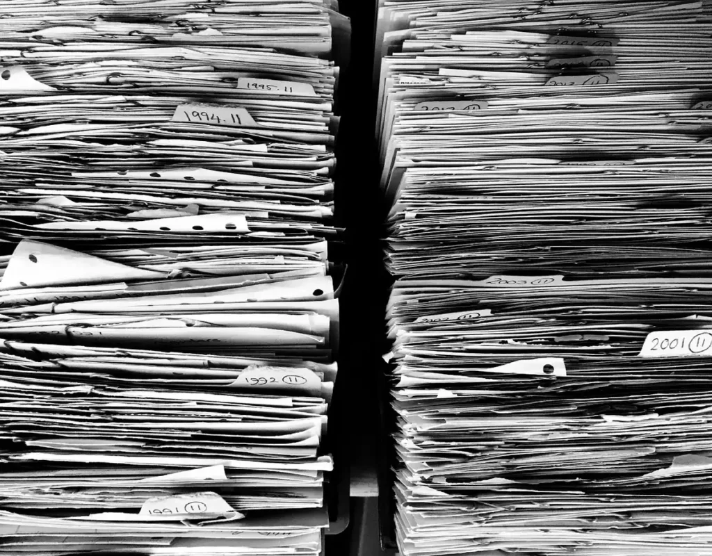 Mains tenant des documents près d'un ordinateur portable dans un bureau lumineux