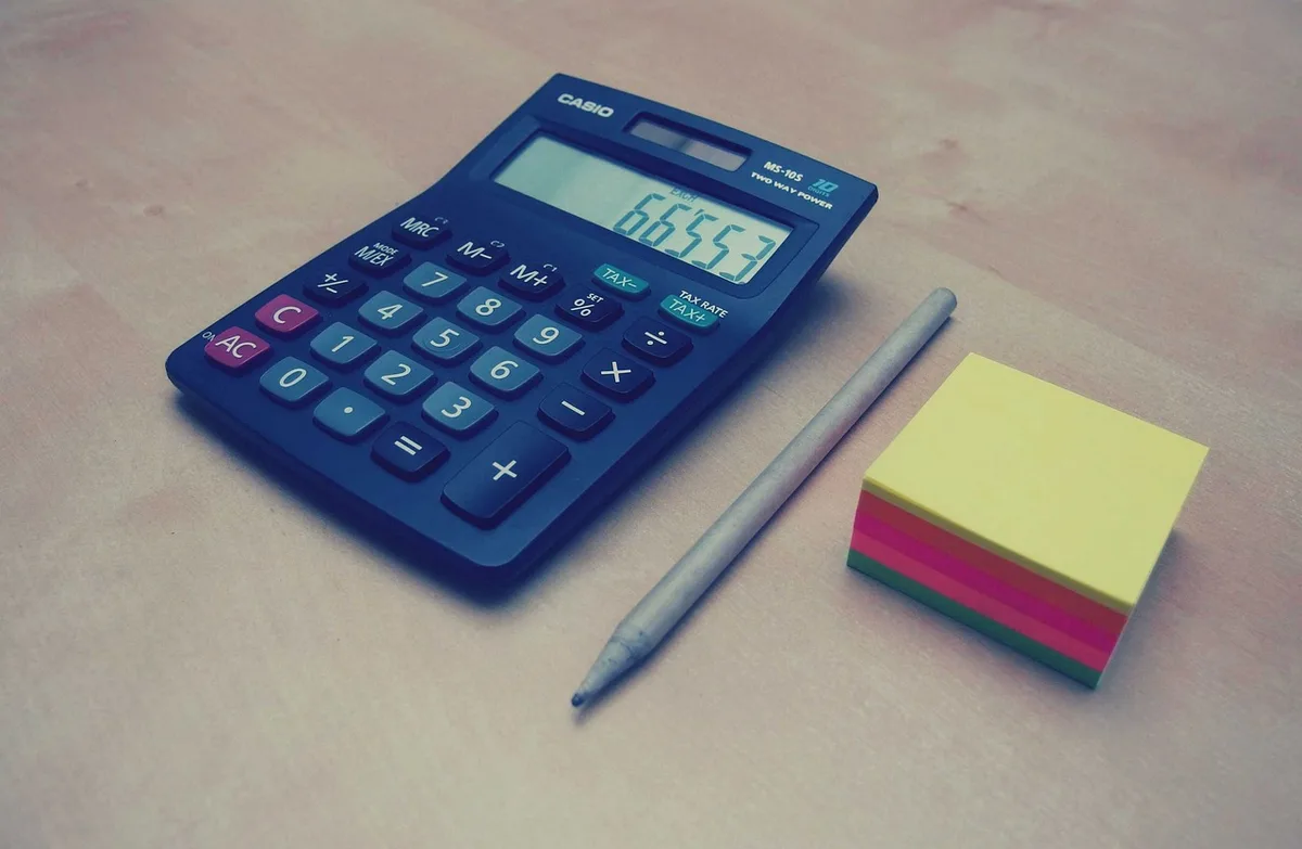 Bureau en pleine journée avec formulaire fiscal et calculatrice, mains en train de remplir