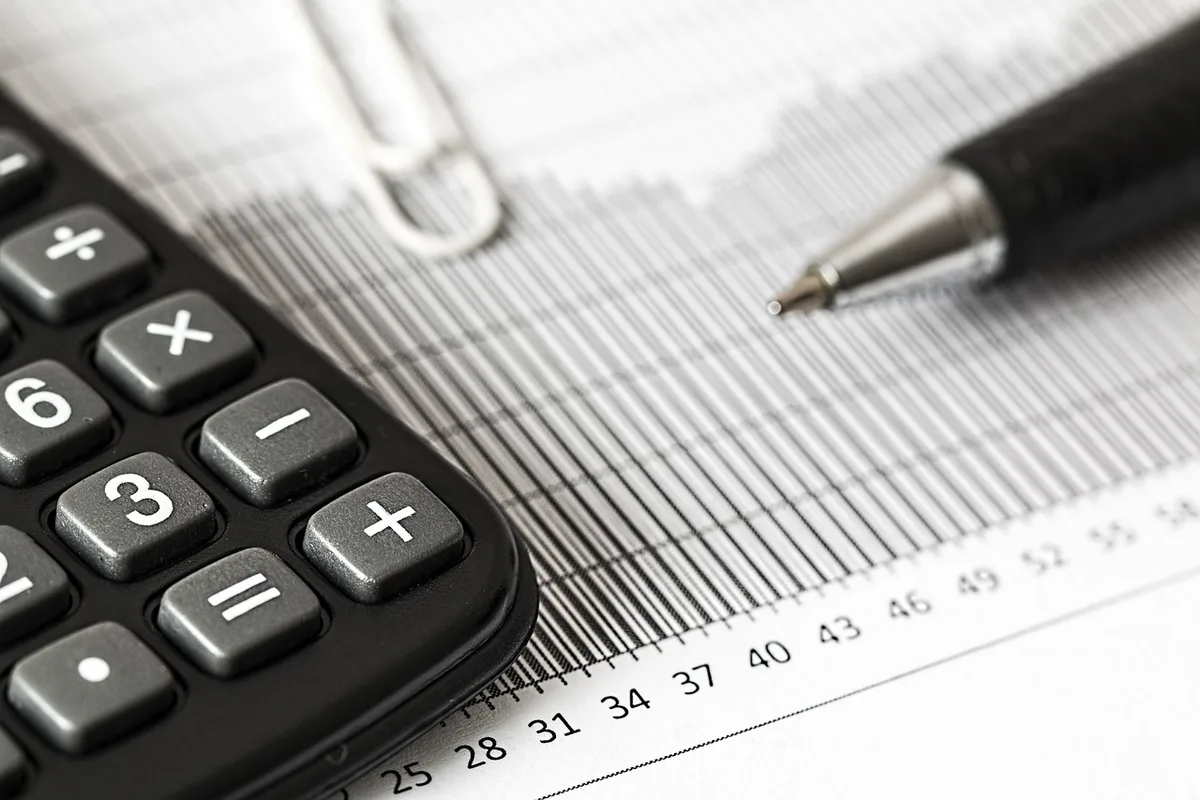 Bureau lumineux avec documents d'investissement, calculatrice et mains qui examinent des fiches