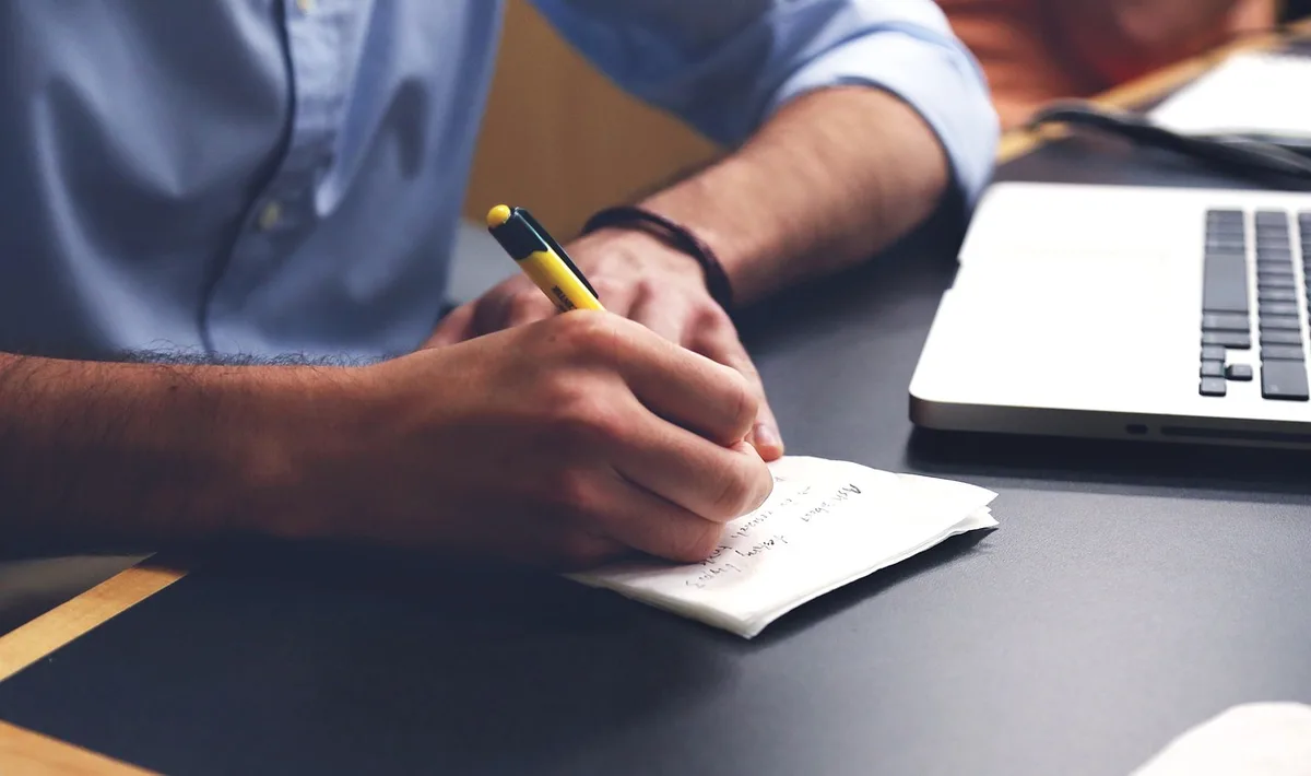 Bureau en journée avec carnet, stylo et ordinateur affichant une checklist