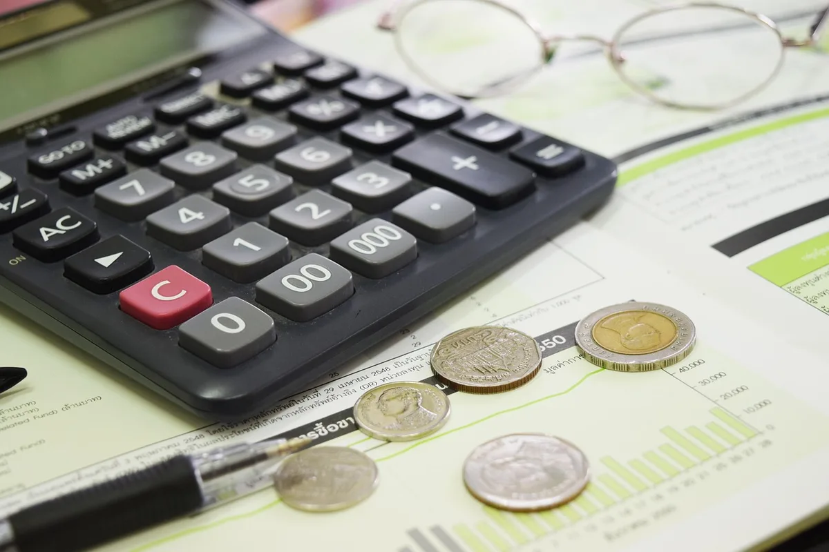 Carnet de budget, calculatrice et tirelire sur une table symbolisant la planification d'un placement
