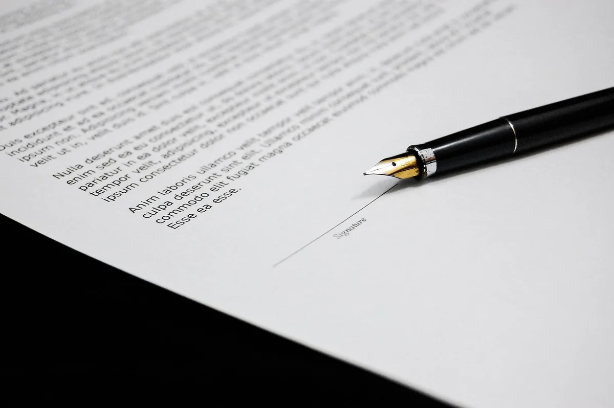 Contrat bancaire et carte posés sur une table avec des mains pointant une clause