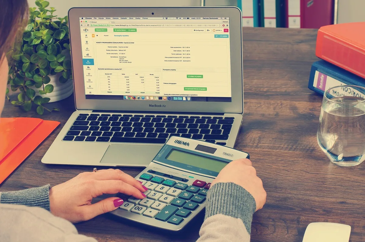 Personne calculant cotisations et revenus sur un bureau en journée