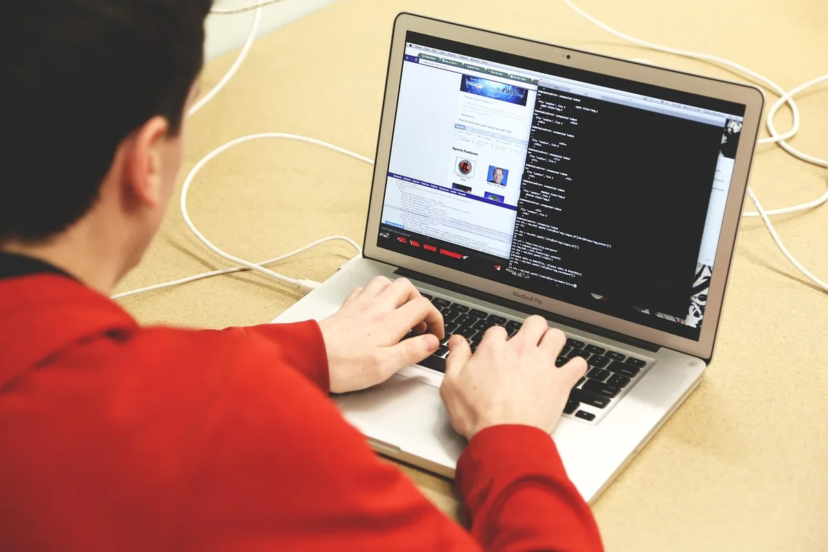 Personne lisant du code de contrat intelligent sur un écran près d'une fenêtre