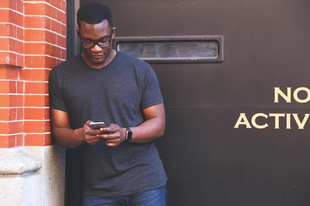 Personne utilisant l'application bancaire sur smartphone à un bureau en pleine journée