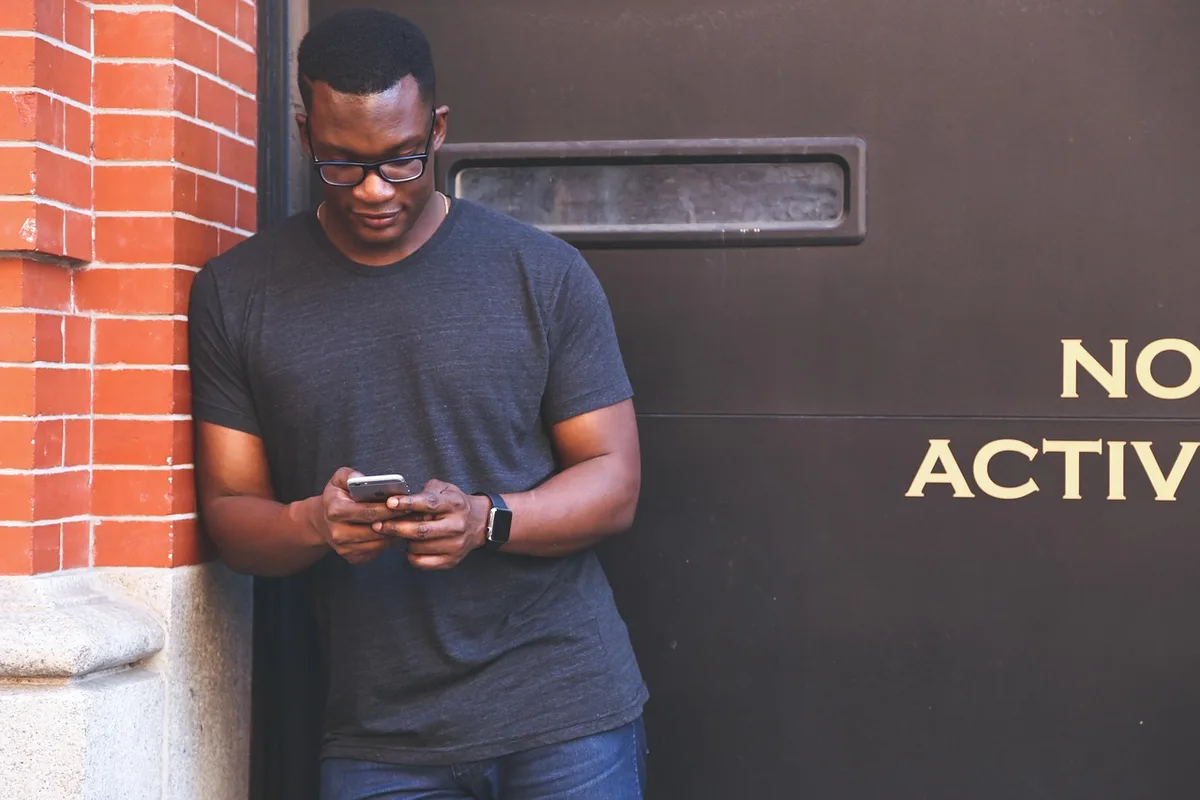 Personne utilisant l'application bancaire sur smartphone à un bureau en pleine journée